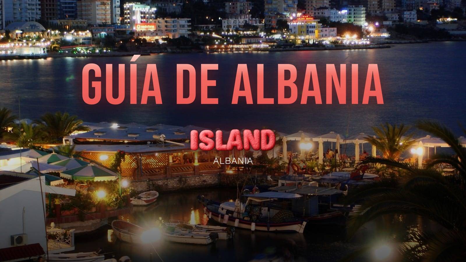 Saranda de noche: el pequeño puerto con sus barcas y una terraza iluminada, y las luces de la ciudad al otro lado de la bahía, con el rótulo de la guía y el logo de Party Island Albania