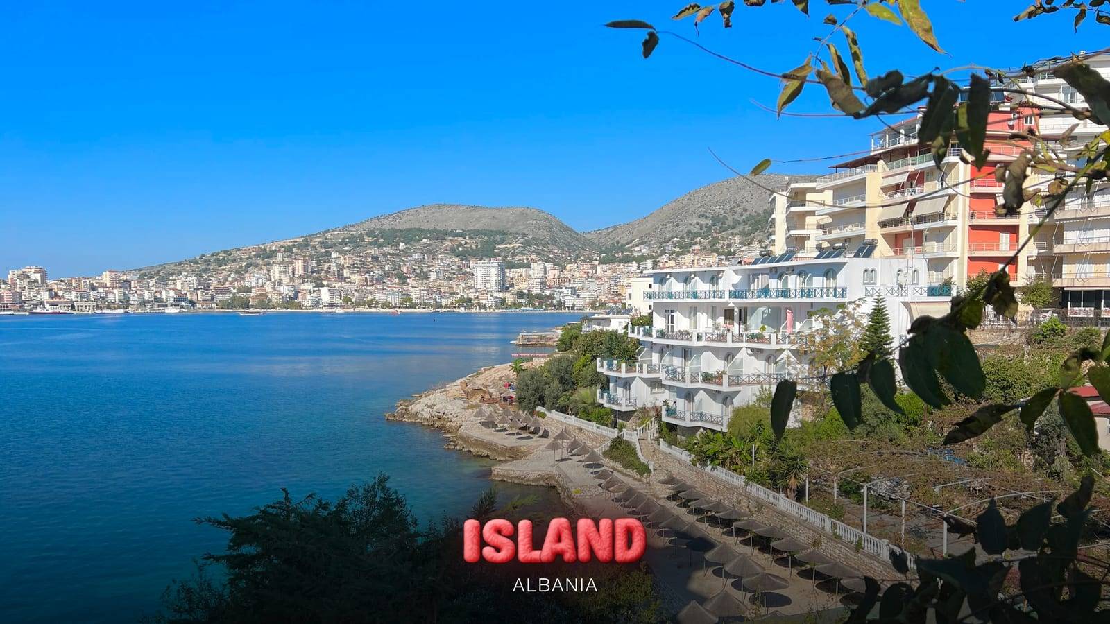 Seafront hotels and the bay of Saranda, Albania, with the Party Island Albania logo